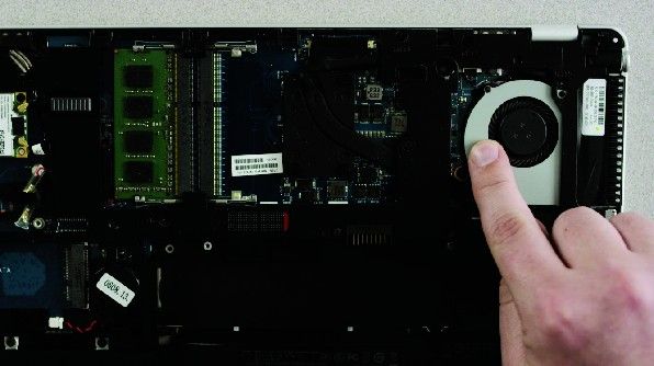 Il dito di una persona tocca una parte di metallo non verniciata sulla parte inferiore esposta del portatile per scaricare l’elettricità statica.